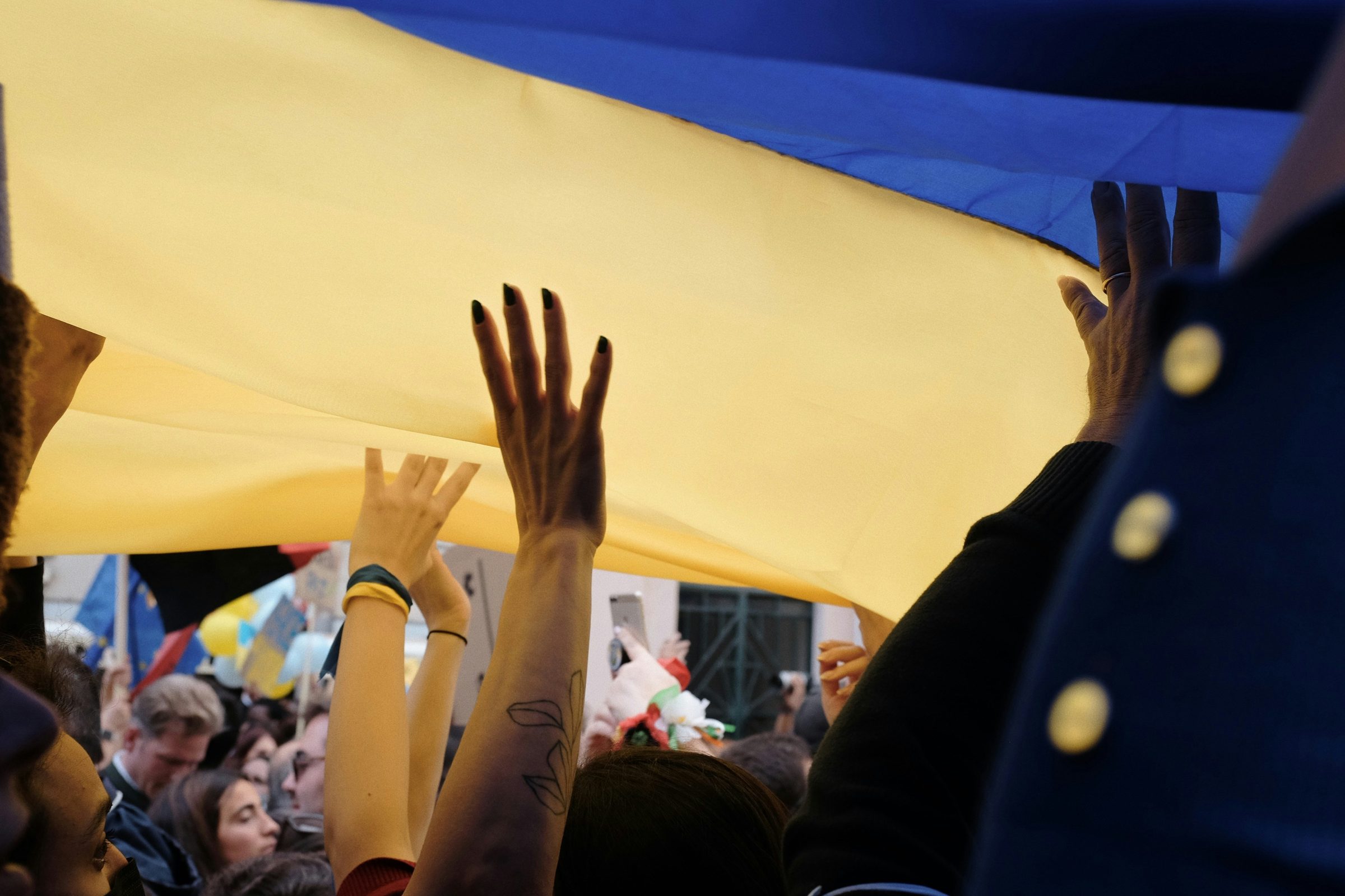 Crowd holding a large Ukrainian flag overhead